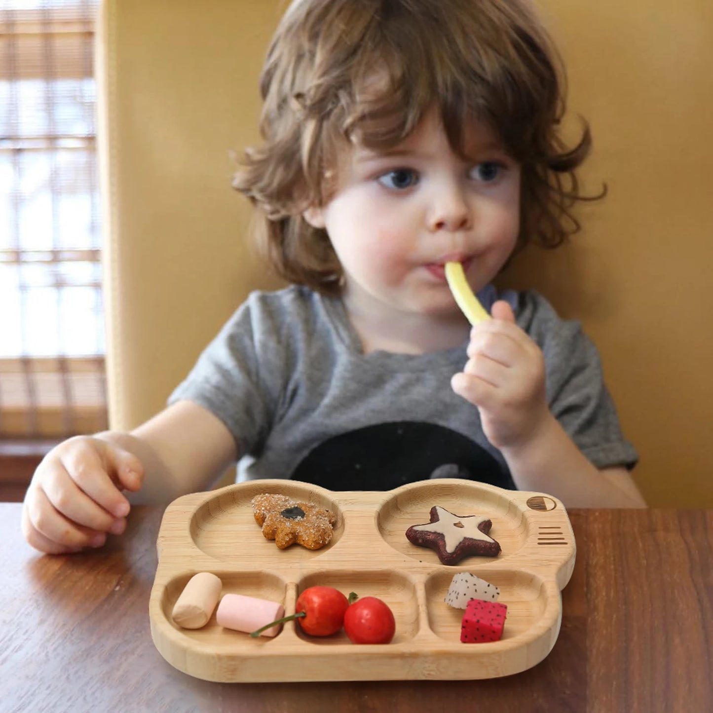 Child eating from a wooden plate with food at a table