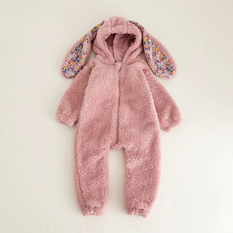 Pink fluffy bunny onesie with floral ears on a light beige background